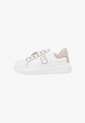 Sneaker bianca low-top con dettagli beige, logo con borchie dorate sul lato, suola spessa e ciondolo decorativo dorato sui lacci beige, vista laterale.