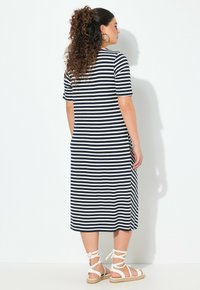 Sukienka midi w paski w kolorze granatowym i kremowym, krótki rękaw, luźny krój, z bocznymi kieszeniami. Noszona z białymi sandałami na paski. Gładka tekstura.