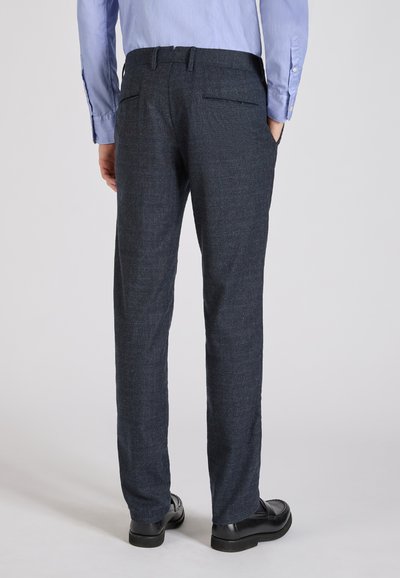 Ciemnoniebieskie, teksturowane spodnie o dopasowanym kroju, z dwiema tylnymi kieszeniami i gładką talią, noszone z czarnymi butami.