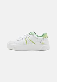 Fehér sneakers zöld részletekkel, texturált bőr felső résszel, kerek orrral és vastag fehér talppal, amelyen finom barázdák találhatók.