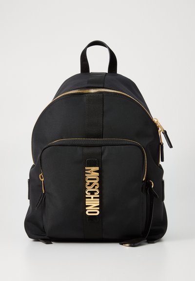 Černý nylonový batoh s prohnutým vrchem, zlatým zipem a logem Moschino v lesklém zlatě. Obsahuje nastavitelné popruhy a přední kapsu na zip.