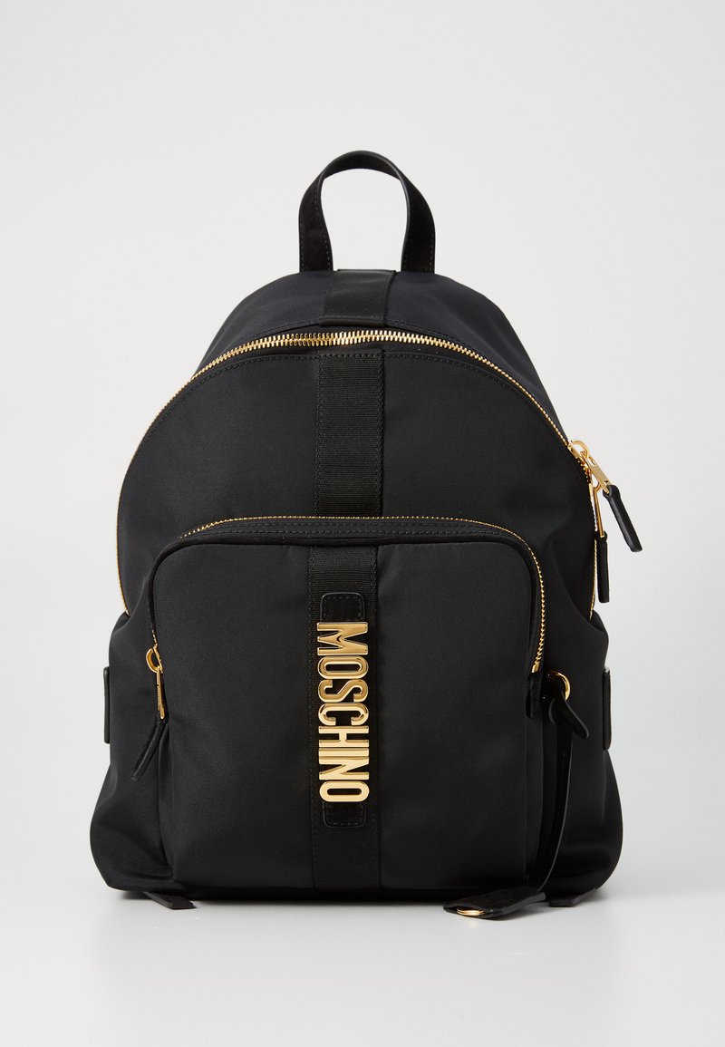 Rucsac negru din nylon, cu un vârf curbat, fermoar auriu și logo Moschino în aur strălucitor. Dispune de bretele ajustabile și un buzunar frontal cu fermoar.
