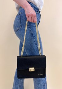 Borsa a tracolla in pelle nera con catena dorata, forma rettangolare, chiusura a scatto frontale e logo nell'angolo in basso a destra.