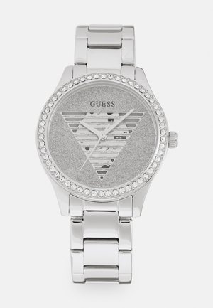 Silberne Uhr mit einem glitzernden grauen Zifferblatt, das ein Design mit dreieckigen Ausschnitten und Kristallakzenten rund um die Lünette aufweist. Armband aus Edelstahl.