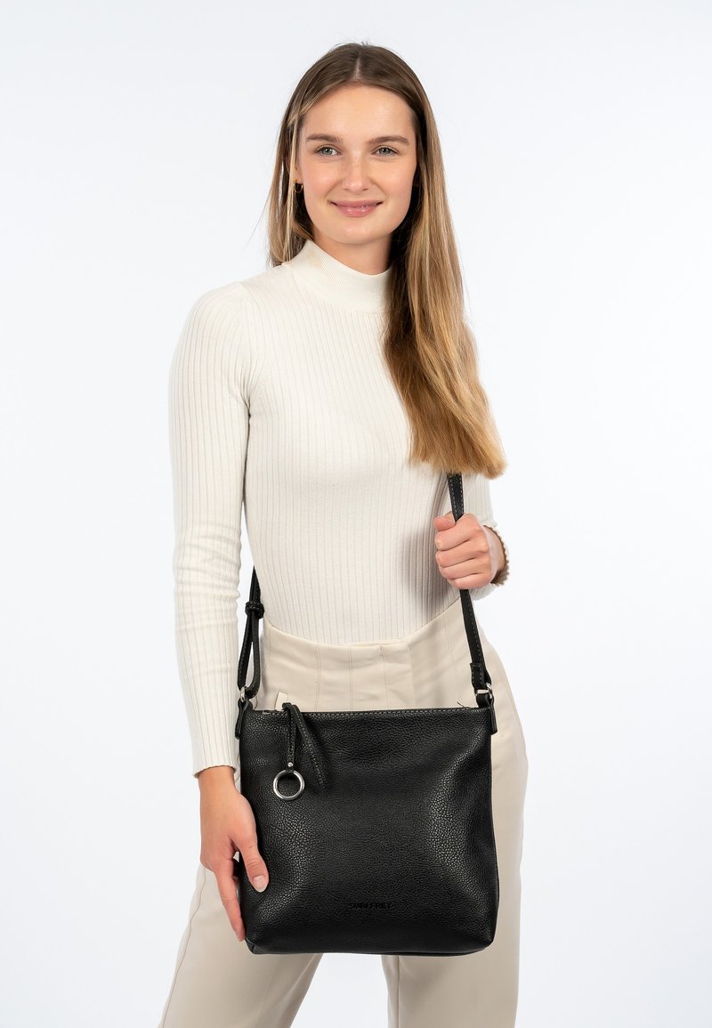 Borsa a tracolla in pelle nera con finitura testurizzata, un accento metallico circolare e una tracolla regolabile. Design semplice e funzionale.