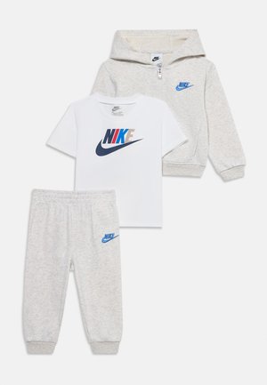 Trzyczęściowy zestaw dziecięcy z jasnoszarą bluzą z kapturem na zamek, dopasowanymi spodenkami dresowymi oraz białym T-shirtem z krótkim rękawem i wielokolorowymi logo Nike.