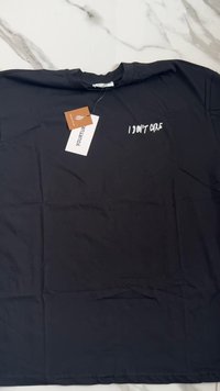 Camiseta de algodón negra con mangas cortas. Presenta el texto blanco "NO ME IMPORTA" en el frente. Incluye etiquetas de papel adjuntas al cuello.