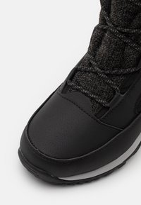 Schwarze wasserdichte Stiefel mit einer strukturierten synthetischen Oberseite, runder Zehenpartie und kontrastierender grauer Sohle; Schnürsystem mit verstärkten Ösen.