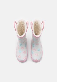 Rubber boots with a light pink interior and handles, featuring a white exterior decorated with pink and blue heart patterns.