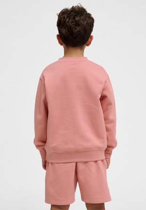 Lyserød sweatshirt og matchende shorts lavet af blødt stof. Lange ærmer, rund halsudskæring og ribbede manchetter. Simpelt design uden mønstre.