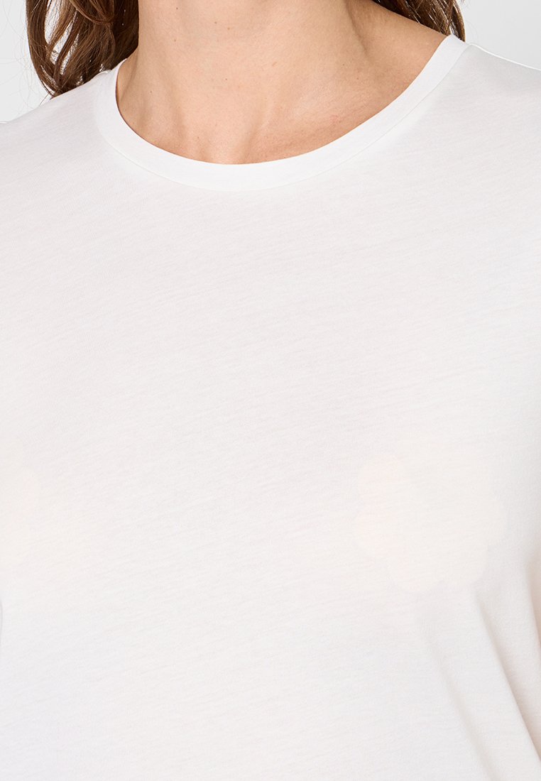 Weißes T-Shirt mit kurzen Ärmeln, runder Ausschnitt und weicher, glatter Textur. Zeigt ein schwaches florales Muster auf dem Stoff.