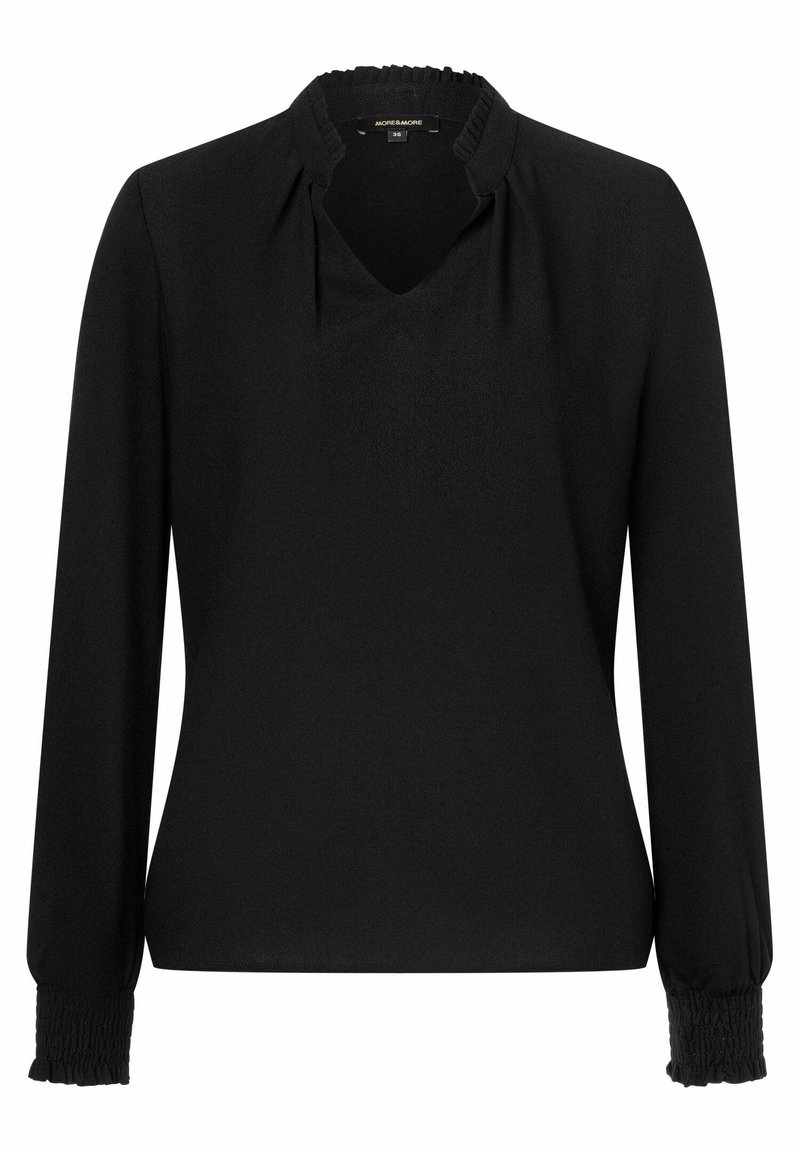 Svart blus med lång ärm, rynkade muddar och en liten volangkrage, med en diskret V-ringning och en slät tygkvalitet.