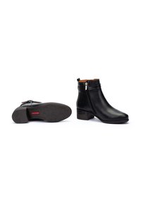Botines negros de piel suave con cremallera lateral, tacón bajo y forro marrón texturizado. Suela de goma duradera con dibujo.