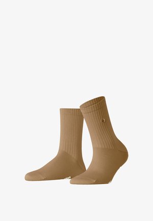 Chaussettes côtelées beiges de longueur mi-mollet, avec un doigt de pied renforcé et un petit logo sur un côté. Texture lisse avec un ajustement confortable.