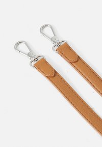 Tan läderremmar med en texturerad yta, försedda med silverfärgade metalldelar i båda ändarna för fäste. Släta kanter och synlig sömdetalj.