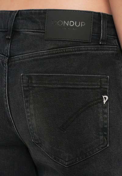 Jeans de mezclilla negros con una parche de cuero etiquetado "DONDUP", con costuras laterales y un acento decorativo en el bolsillo.