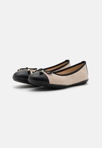 Ballerines en cuir beige avec un capuchon noir, ornées d'un accent en nœud et de détails en doré. Semelle flexible pour plus de confort.