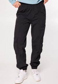 Zwarte cargo broek gemaakt van lichtgewicht materiaal, met een elastische tailleband, zijzakken en gathered cuffs. Draag met witte sneakers.