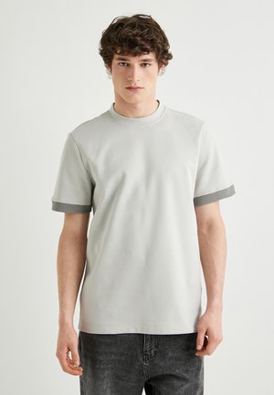 Lys grå kortærmet t-shirt med ribbet rund hals og mørkegrå detaljer ved ærmerne, lavet af blødt og behageligt stof.