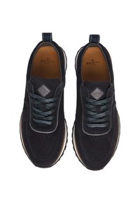 Las zapatillas de ante azul marino cuentan con un collar acolchado, cordones en verde oscuro y una plantilla de cuero marrón. Punta redonda con una suela de goma y acentos mínimos.