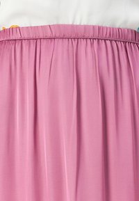 Rosa, lett skjørt med elastisk midje. Har en myk, glatt tekstur og milde plisseringer, egnet for hverdagsbruk.