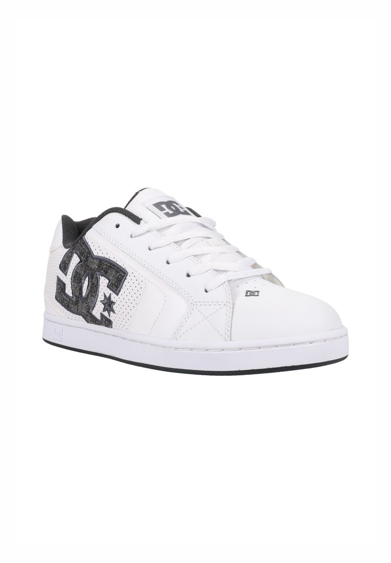 Witte sneaker met zwarte accenten, voorzien van een gestructureerd patroon en geperforeerd ontwerp. Inclusief veters en logo-detail aan de zijkant.