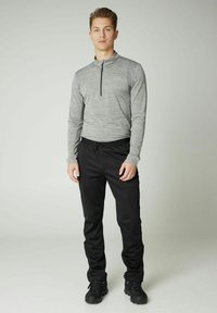 Graues langärmeliges Quarter-Zip-Oberteil mit kontrastierenden Ärmeln, kombiniert mit schwarzen Jogginghosen mit Kordelzug und schwarzem Schuhwerk. Glatte Textur, athletische Passform.