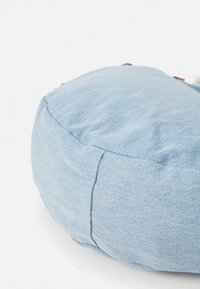 Cuscino rotondo in denim blu con una superficie liscia, caratterizzato da dettagli di cucitura visibili e un imbottitura morbida, adatto per sedersi o come decorazione.