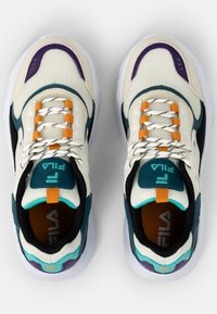 Chunky Sneaker mit einem cremefarbenen Mesh-Obermaterial, das mit türkisfarbenen, lila und orangefarbenen Akzenten sowie kontrastierenden schwarzen Abschnitten und einer weißen Sohle versehen ist.
