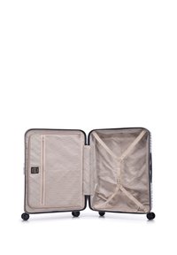 Hard-shell koffer in zwart en wit met een geometrisch patroon, voorzien van een beige interieur, een ritsvak en kruisbanden voor organisatie.