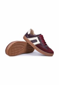 Paire de baskets basses décontractées en cuir bordeaux et violet foncé, détail blanc sur le côté, lacets rouges et semelles en caoutchouc marron, sur fond blanc.