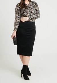 Leopardenmuster Langarmoberteil, taillierter schwarzer Midirock, elegante schwarze Handtasche und schwarze Stiefel mit Absatz und geripptem Knöcheldetail.