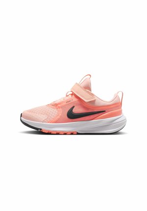 Zapatilla Nike en rosa claro y coral con logo negro, suela blanca y cierre de velcro, mostrada de lado sobre un fondo blanco.