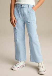 Pantalons cargo rayés bleu et blanc, design à jambe large, fabriqués en tissu léger, avec poches avant et coupe décontractée.