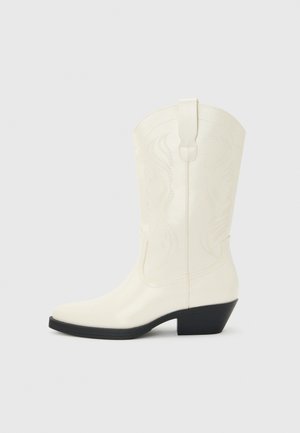 White mid-calf western-style boot with pointed toe, black stacked heel, decorative stitching, and pull tab on the shaft.