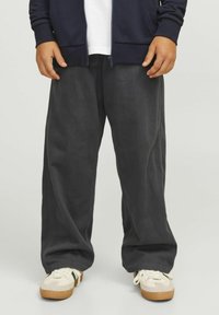 Temno sivi široki hlače, narejene iz mehkega blaga z gladko teksturo, z detajli na stranskih šivih, v kombinaciji s kremnimi supergami.