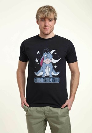 Black cotton t-shirt featuring a printed Eeyore illustration, stars, and a crescent moon, with the text "NOT A MORNING PERSON" below.