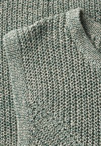 Pull en tricot texturé dans un mélange de fils turquoise et blancs, présentant un col côtelé et une apparence douce et confortable.