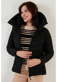 Black puffer jacket with a high collar, quilted design, and zippered front. Warm, lightweight material with a smooth texture.