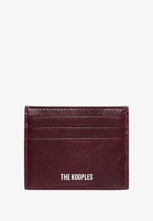 Tarjetero de cuero rojo oscuro con cuatro ranuras para tarjetas y "THE KOOPLES" grabado en blanco en la parte inferior central.