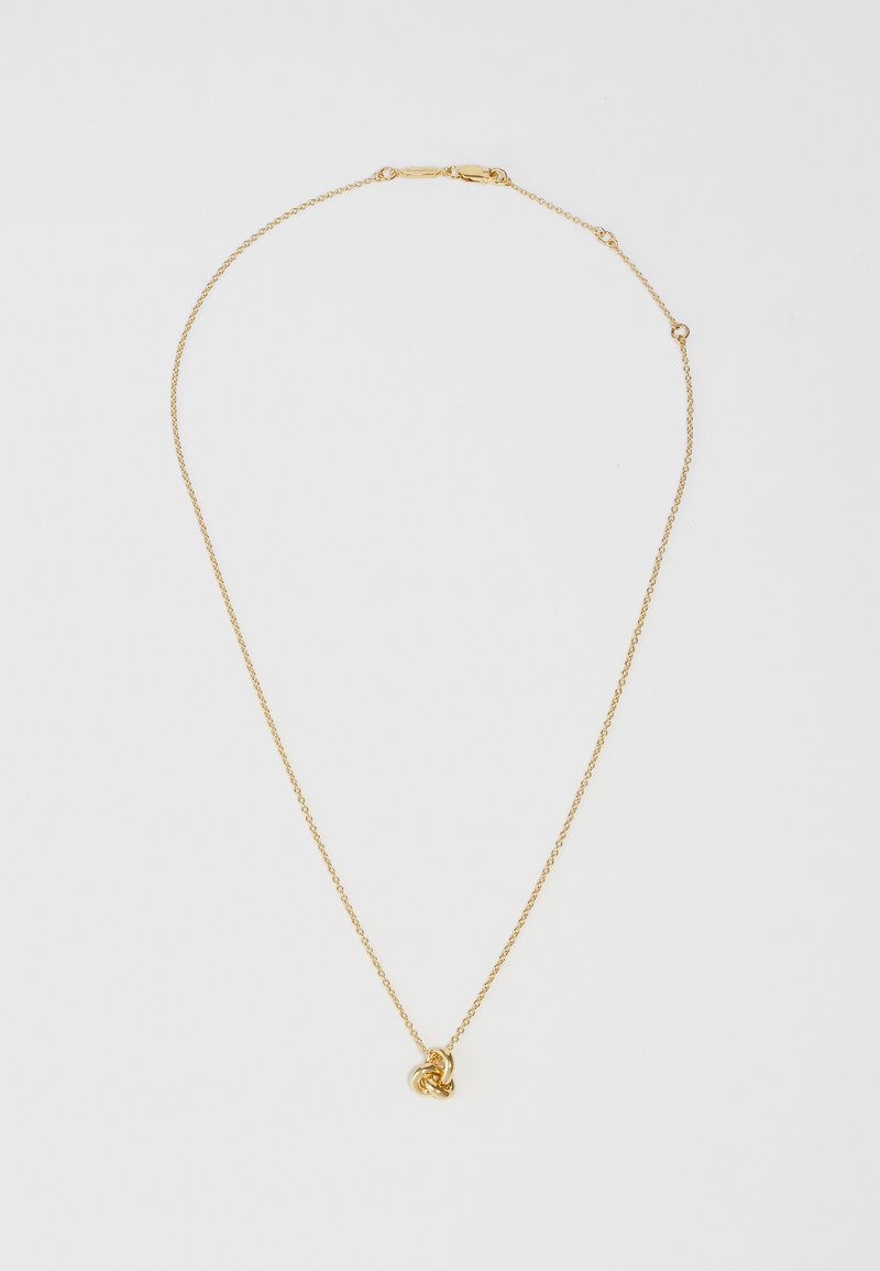 Collana d'oro con una delicata catena e un pendente a forma di cuore con nodo. La superficie è liscia con una finitura lucida, creando una leggera lucentezza.