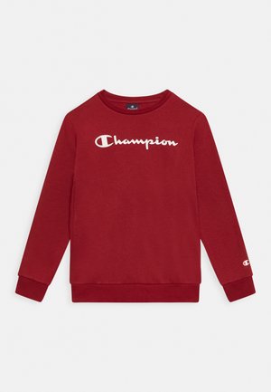 Sudadera roja de manga larga con cuello redondo y logo blanco de Champion en el pecho, además de un pequeño logo en el puño de la manga izquierda.