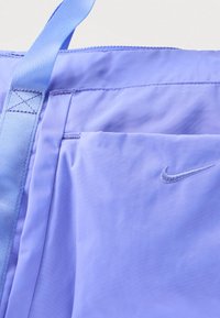 Αθλητική τσάντα Nike σε λεβάντα χρώμα με εμφανές μπροστινό τσεπάκι, μπλε λουρί και κεντημένο λογότυπο Nike Swoosh στην υφασμάτινη επιφάνεια.