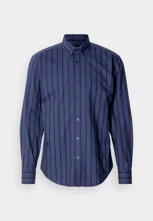 Tengerészkék hosszú ujjú ing függőleges csíkokkal, gombos nyakkal és finom logóval. Ívelt alsó szegély és gombos díszítések jellemzik.