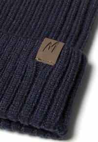 Beanie a coste blu navy realizzato in morbida lana, con un'etichetta in pelle marrone con logo stampato; design caldo e flessibile.
