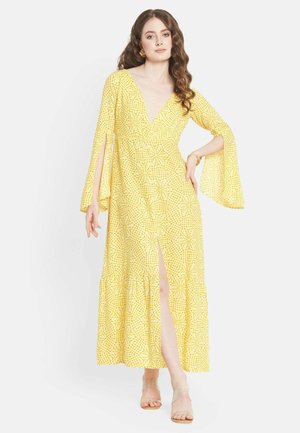 Gelbes Maxikleid mit V-Ausschnitt, Glockenärmeln und einem Schlitz vorne. Es hat ein Karomuster und einen luftigen Saum. Das Material wirkt leicht.