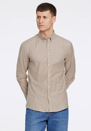 Beige langslip shirt met knopen en een kraag, met een gladde textuur en een normale pasvorm, gecombineerd met blauwe jeans.