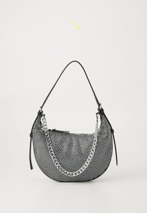 Black and white polka dot crescent handbag with black strap and silver chain detail on a white background.
