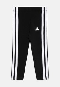 Leggings deportivos negros con tres rayas verticales blancas a lo largo de cada lado y un pequeño logotipo blanco de Adidas en el muslo izquierdo.