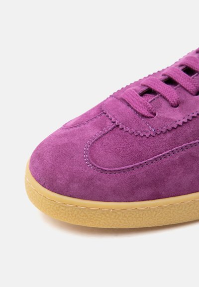 Baskets en daim violet avec lacets assortis et semelle en caoutchouc marron clair texturée, vues en gros plan.